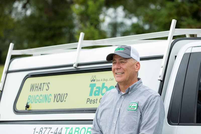 A Tabor Pest Control team member standing by the company truck