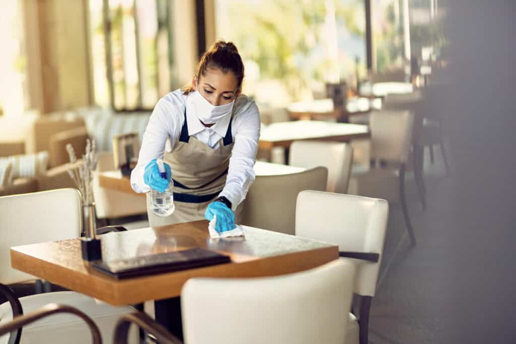 A waitress is proactively cleaning a restaurant table to prevent pests